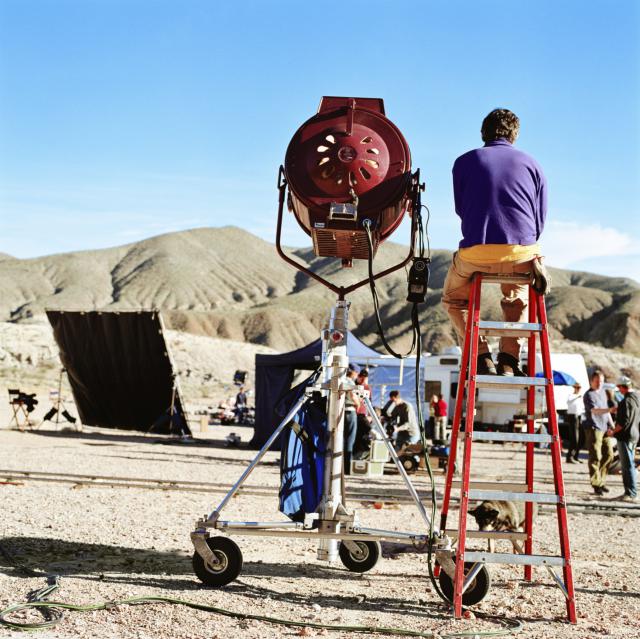 Film crew in desert, spotlight in foreground